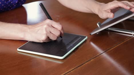 Female-designer-hands-using-a-drawing-graphics-tablet-and-a-laptop.