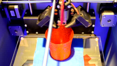 3D-printer-creates-a-round-red-vase,-view-from-above