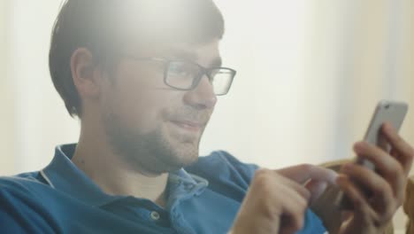 Man-is-Sitting-on-Couch-and-Using-Mobile-Phone