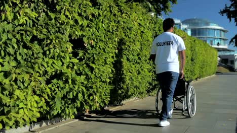 Rear-view-of-a-merciful-volunteer-pushing-a-wheelchair