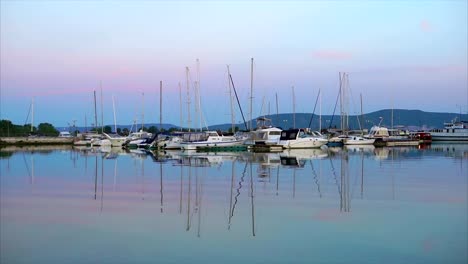 Eine-ruhige-Seenlandschaft,-eine-kleine-Yacht-mit-einem-abgesenkten-Stand-im-Hafen-am-Abend