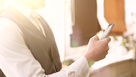 Rich-man-sitting-in-sunlit-room-and-checking-business-news-on-mobile-phone