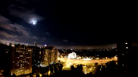 Luna-timelaps-de-ciudad-de-noche-en-noche-de-luna-de-una-zona-residencial-cerca-de-la-autopista-de-alta-velocidad-con-coches-rápidos.-Nubes-pasando-por-fuul-moon-en-ciudad-de-la-noche.-Nightclouds-volar-rápidamente-a-través-del-cielo