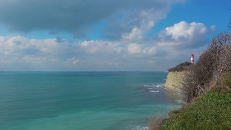 Lighthouse-and-ocean-coast-cliff-at-beautiful-day,-ships-in-the-distance.