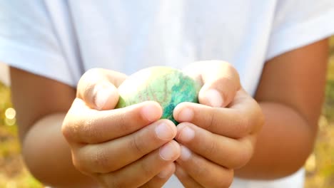 Primer-plano-de-la-mano-de-los-niños-con-un-huevos-de-Pascua-en-fondo-sol