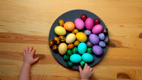 Children's-hands-take-colored-Easter-eggs-from-a-plate