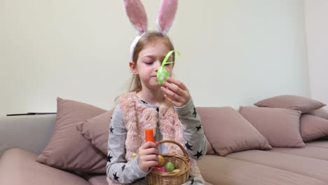 Girl-with-bunny-ears-and-decorative-Easter-eggs-eating-carrot