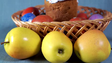 Close-up,-Easter-Arrangement,-Easter-in-the-Wooden-Basket-with-Dyed-Eggs-and-Apple-on-the-Background