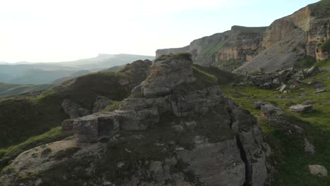 Flying-around-a-large-rock-formation-standing-at-the-foot-of-the-epic-edge-of-a-rocky-plateau.-Russia.-North-Caucasus