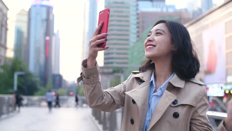 lenta-de-mujer-asiática-joven-muy-feliz-caminando-en-la-calle-durante-el-uso-de-teléfonos-inteligentes-en-la-tarde-de-la-ciudad