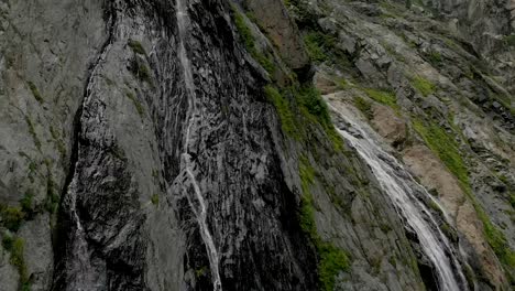 Tracking-and-top-shot-Air-shot-from-a-stream-of-water-splashing-waterfall-on-a-rock-wall-in-the-Caucasus-Mountains.-Around-the-jet-of-the-waterfall