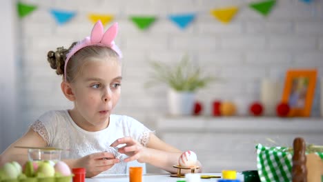 Niña-comiendo-secretamente-huevo-de-chocolate,-infantil,-preparación-para-la-Pascua