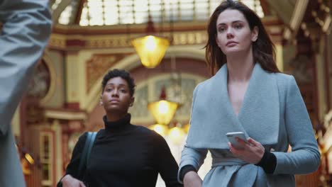 Millennial-business-people-walking-towards-camera-in-Londonês-historical-Leadenhall-covered-street-market,-low-angle