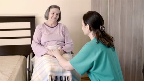 Mujer-anciana-en-silla-de-ruedas-en-casa-de-reposo-con-su-asistente-de-cuidado