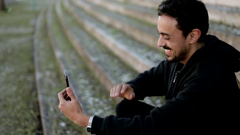 Joven-árabe-hombre-teniendo-video-chat-fuera,-agitando-la-mano