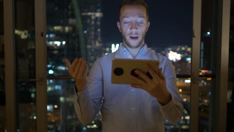 Young-man-using-tablet-to-speak-and-communicate-with-skyscraper-view-background