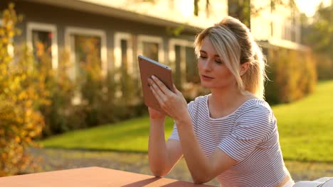 Junge-schöne-Geschäftsfrau-sitzt-an-einem-Tisch-mit-Tablet-in-den-Händen