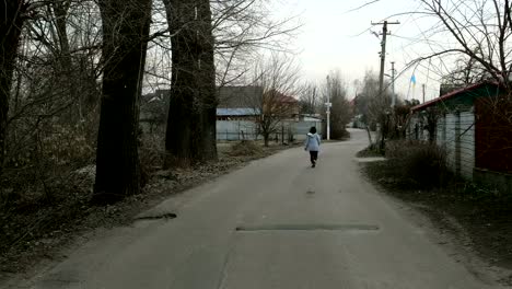 Sola-mujer-camina-a-lo-largo-de-la-carretera-entre-las-casas-y-los-árboles.