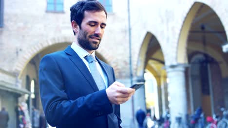 Un-hombre-de-negocios-contestar-el-teléfono,-enviar-mensajes-y-sonrisas-para-las-hermosas-noticias-de-trabajo-y-en-el-fondo-se-ve-a-un-pueblo.