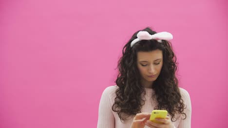 Beautiful-young-girl-standing-on-a-pink-background.-During-this,-there-are-ears-of-rabbits-on-the-head.