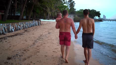 feliz-pareja-gay-está-descansando-en-una-hermosa-playa-tropical.-Concepto-LGBT.-Pareja-Gay-caminando-en-la-playa-con-un-niño