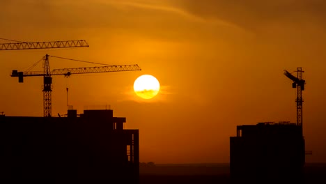 The-building-with-cranes-on-the-sunset-background.-time-lapse