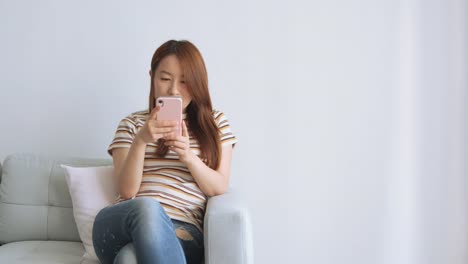 Mujer-asiática-usando-teléfono-celular-en-la-sala-de-estar