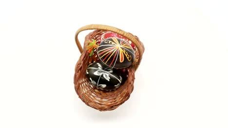 decorative-basket-with-painted-Easter-eggs-on-white-background