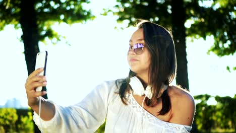 Smiling-Teenager-taking-selfie-video-using-smartphone-outdoors