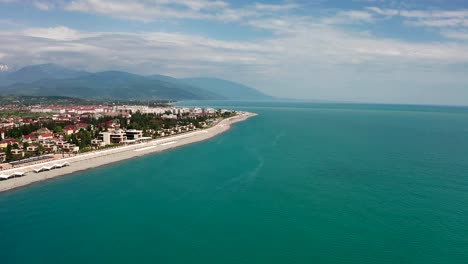 Toma-de-video-aéreo.-La-costa-del-mar-negro-de-la-región-de-Krasnodar,-Sochi.-Imeretinskaya.-Playa-equipada.-Zona-recreativa.-Disparos-panorámicos.-Cielo-azul.-Agua-de-mar-limpia.