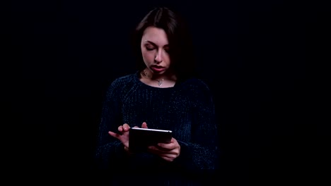 Closeup-portrait-of-adult-beautiful-caucasian-brunette-female-texting-on-the-tablet-with-background-isolated-on-black