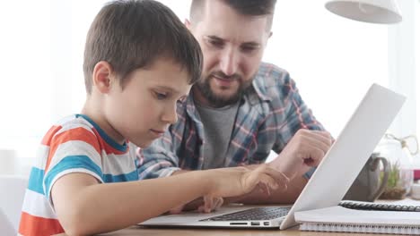 Father-guiding-his-son-to-use-laptop