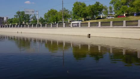 Flying-along-the-city-river-,-over-and-under-the-ancient-stone-bridge.