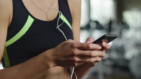 A-beautiful-young-woman-smiles-while-read-a-message,call-her-friends,-using-a-social-network-and-listen-to-the-music-at-the-gym.