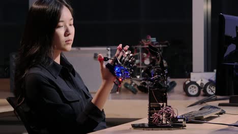 Asiatische-Frau-versuchen,-Roboter-Hand-im-Labor-zu-steuern.-Technologie--und-Innovationskonzept.