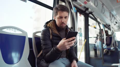 Mann-fährt-Bus-und-schaut-auf-dem-Bildschirm-des-Smartphones