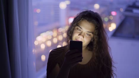 Close-up-woman-using-phone-against-big-window-at-twilight