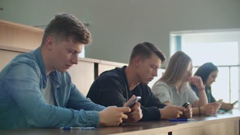 Multi-Ethnische-Gruppe-von-Studenten-mit-Smartphones-während-der-Vorlesung.-Junge-Menschen,-die-soziale-Medien-während-des-Studiums-an-der-Universität-nutzen.