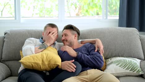 Pareja-gay-relajándose-en-el-sofá-viendo-la-televisión.-Salta-el-susto.