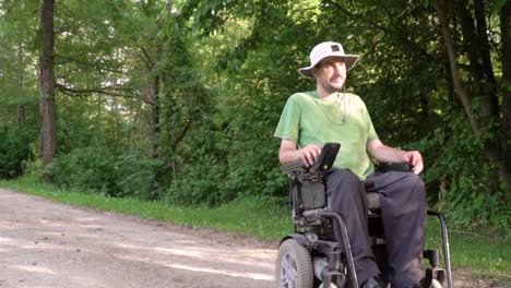 Slowmotion-follow-of-disabled-young-man-in-a-wheelchair-observing-nature-around-him