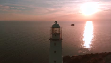 Lighthouse-on-the-cape.-beautiful-shot-from-the-air,-flying-over-the-lighthouse-during-sunset,-beautiful-light,-scenic-landscape-sky-and-sea,-Suristic-colors.-Flying-around-the-lighthouse