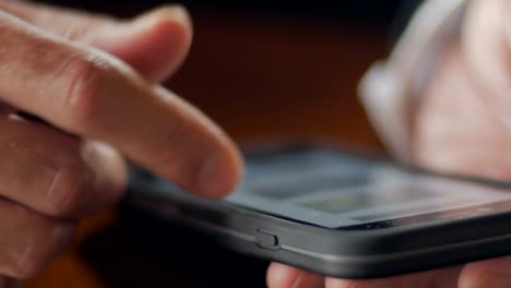 Extreme-closeup-of-mans-hands-scrolling-through-mobile-phone---dolly