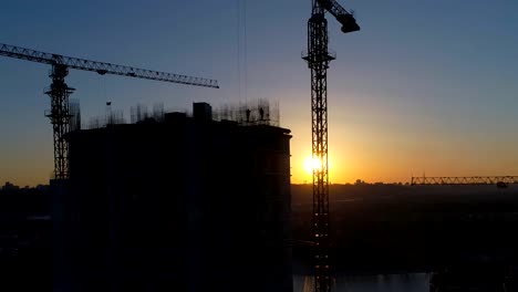 Aerial-shot-of-construction-site-with-cranes-and-workers-at-sunset