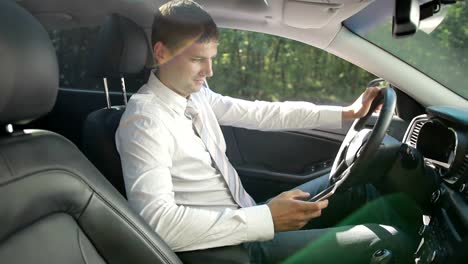 Smiling-bussinessman-in-car-texting-on-smartphone