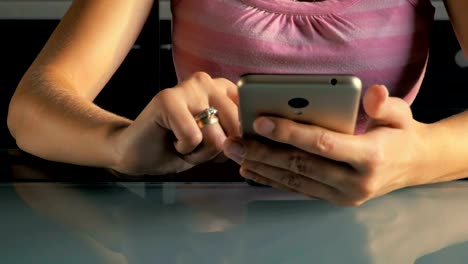 Young-girl-sits-at-the-table-and-read-on-the-smartphone-in-the-kitchen-at-home.