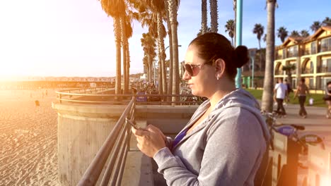 Video-de-mujer-con-teléfono-móvil-en-el-malecón-de-4K