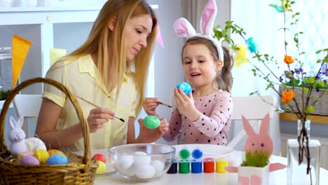 Happy-Easter!-Mother-and-her-little-daughter-wearing-funny-rabbit-ears-coloring-easter-eggs