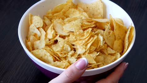 Großer-Teller-mit-Kartoffel-Chips-auf-dem-Tisch.-Weibliche-Hände-mit-schönen-Maniküre-nehmen-chips