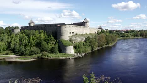 Beautiful-cityscape,-medieval-touristic-attraction-on-Russian-Estonian-border,-Ivangorod-fortress-on-banks-of-Narva-river,-cloudy-sky-horizon