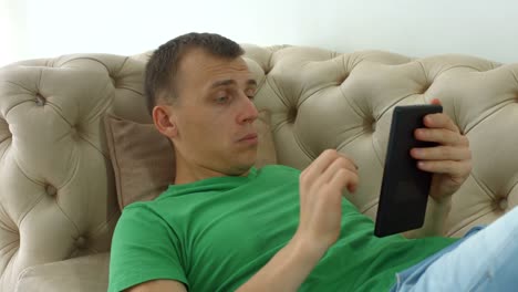 Joyful-man-websurfing-with-tablet-pc-on-the-couch